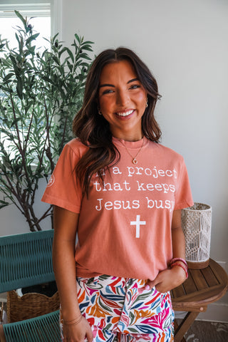 I’m A Project That Keeps Jesus Busy Graphic Tee • Peach