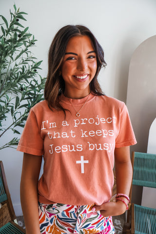 I’m A Project That Keeps Jesus Busy Graphic Tee • Peach